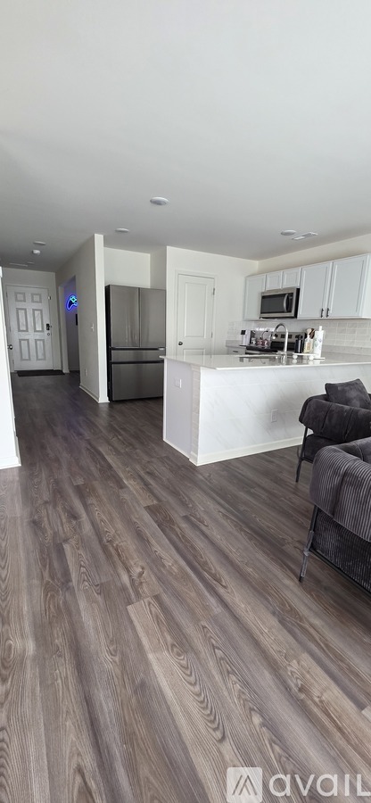 A kitchen with a white countertop and a grey couch.