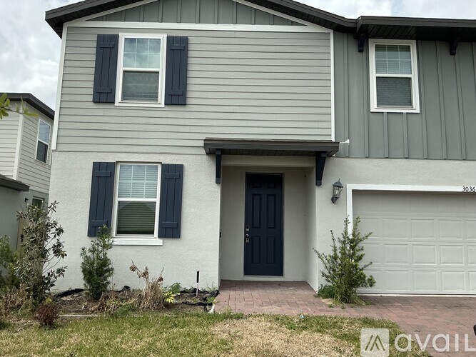 A grey house with a black door and a small front yard.