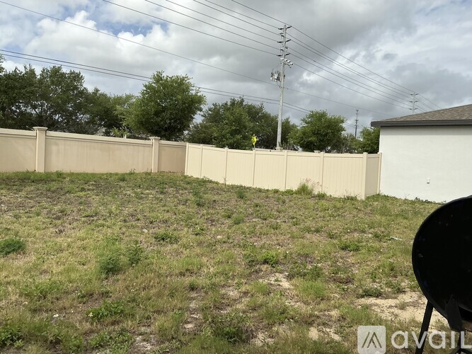 A grassy field with a fence and power lines in the background.