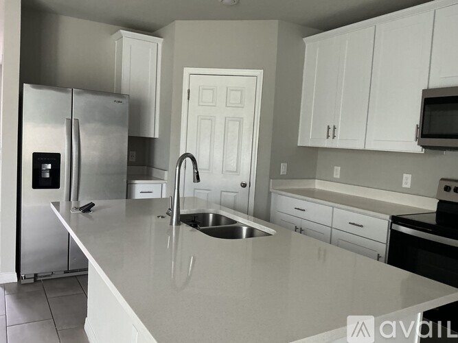 A kitchen with white cabinets and a stainless steel refrigerator.