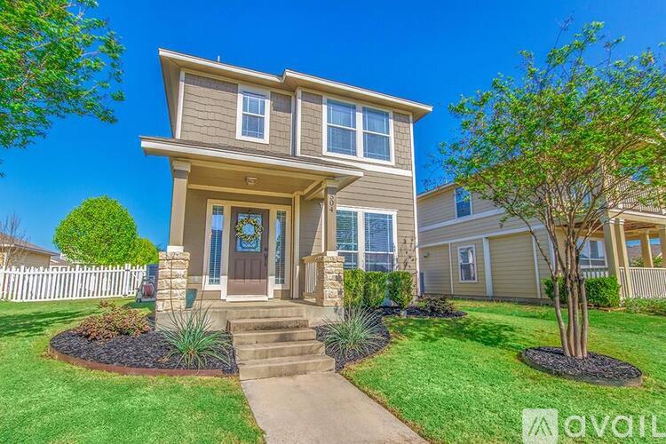 A house with a front yard and a tree in front of it.