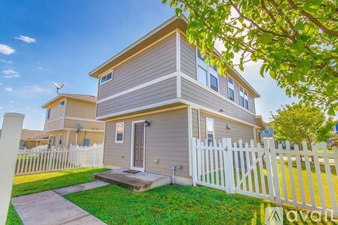 A two-story house with a white picket fence in front.