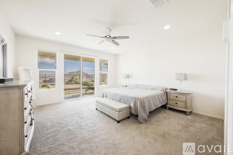 A bedroom with a large bed, a dresser, and a ceiling fan.