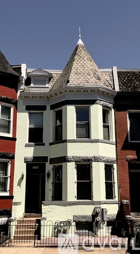 A white house with a brown roof and a black door.