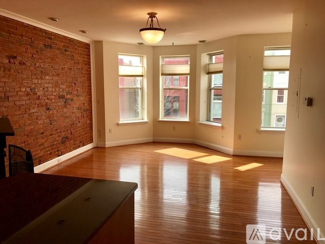A room with a brick wall and wooden floors is available for rent.