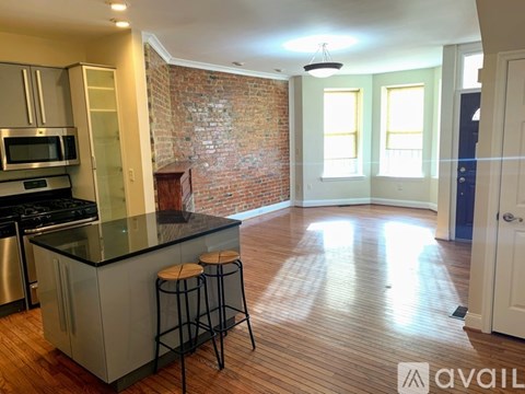 A kitchen with a brick wall and wooden floors.