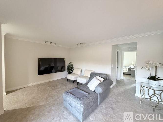 A living room with a grey couch and a flat screen TV mounted on the wall.