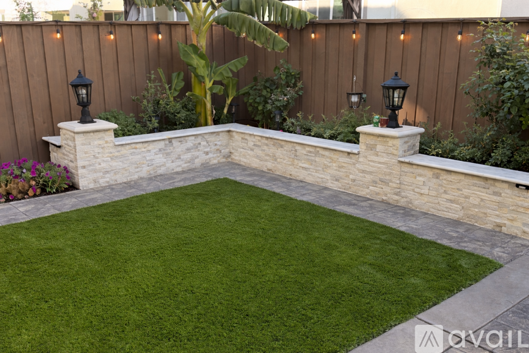 A backyard with a lawn and a stone wall.