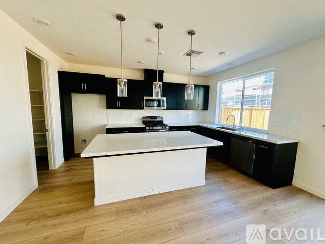 A kitchen with a white island and black cabinets.