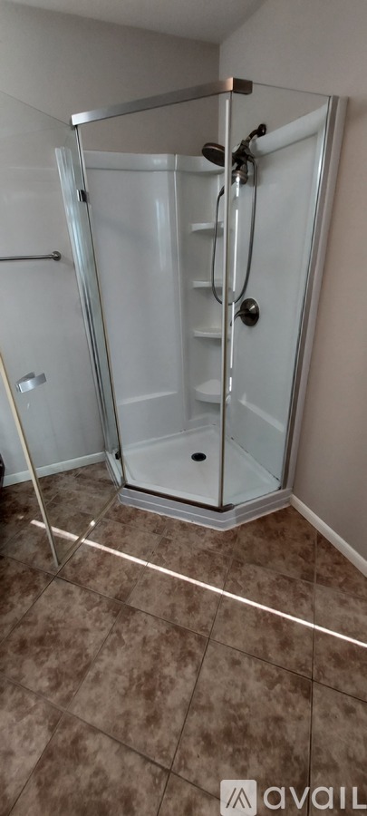 A shower with a glass door and a brown tile floor.