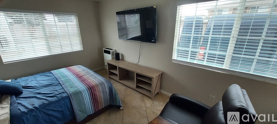 A bedroom with a bed, a chair, and a television.