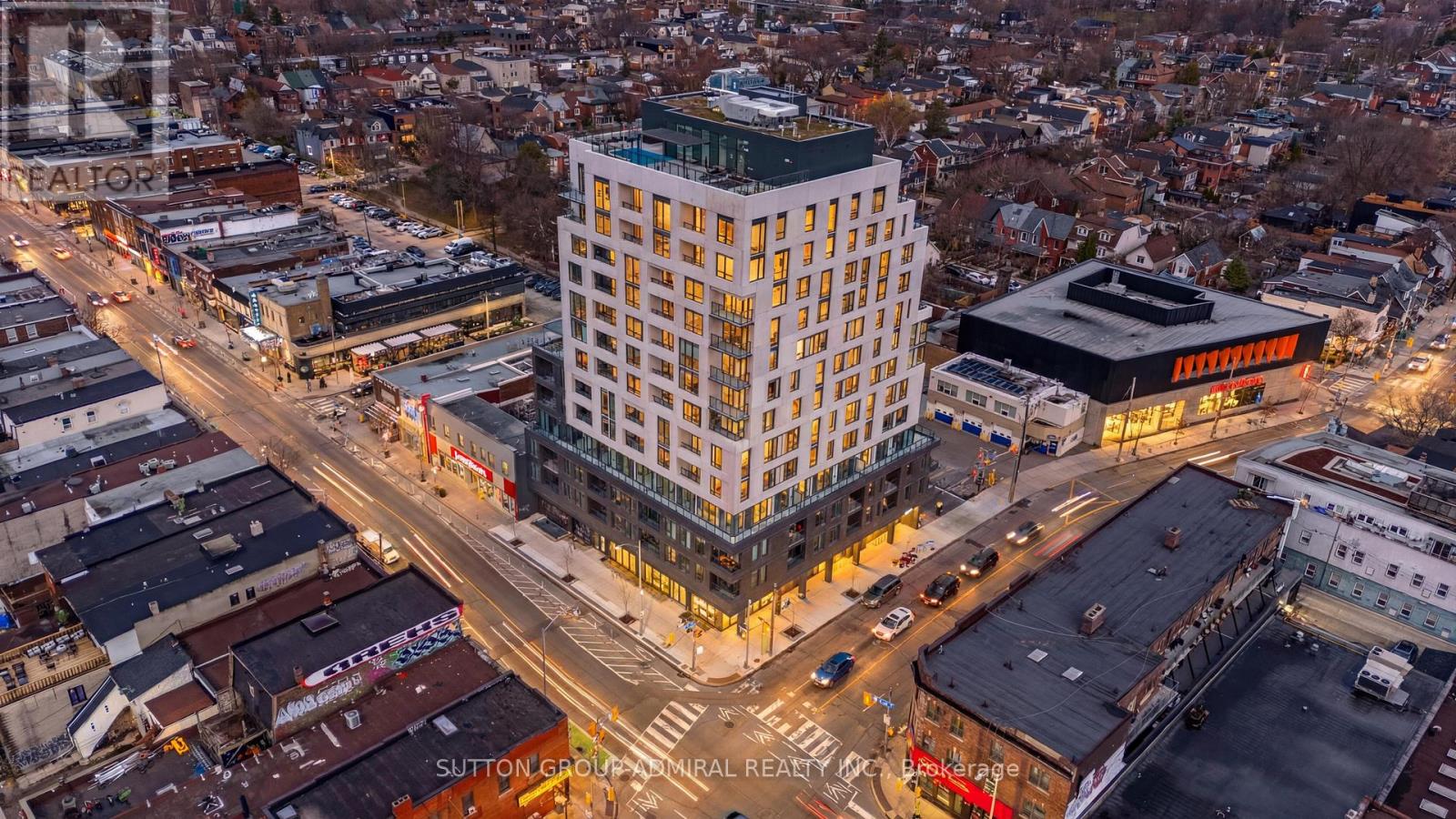 A tall white building with a green roof is in the middle of a city intersection.