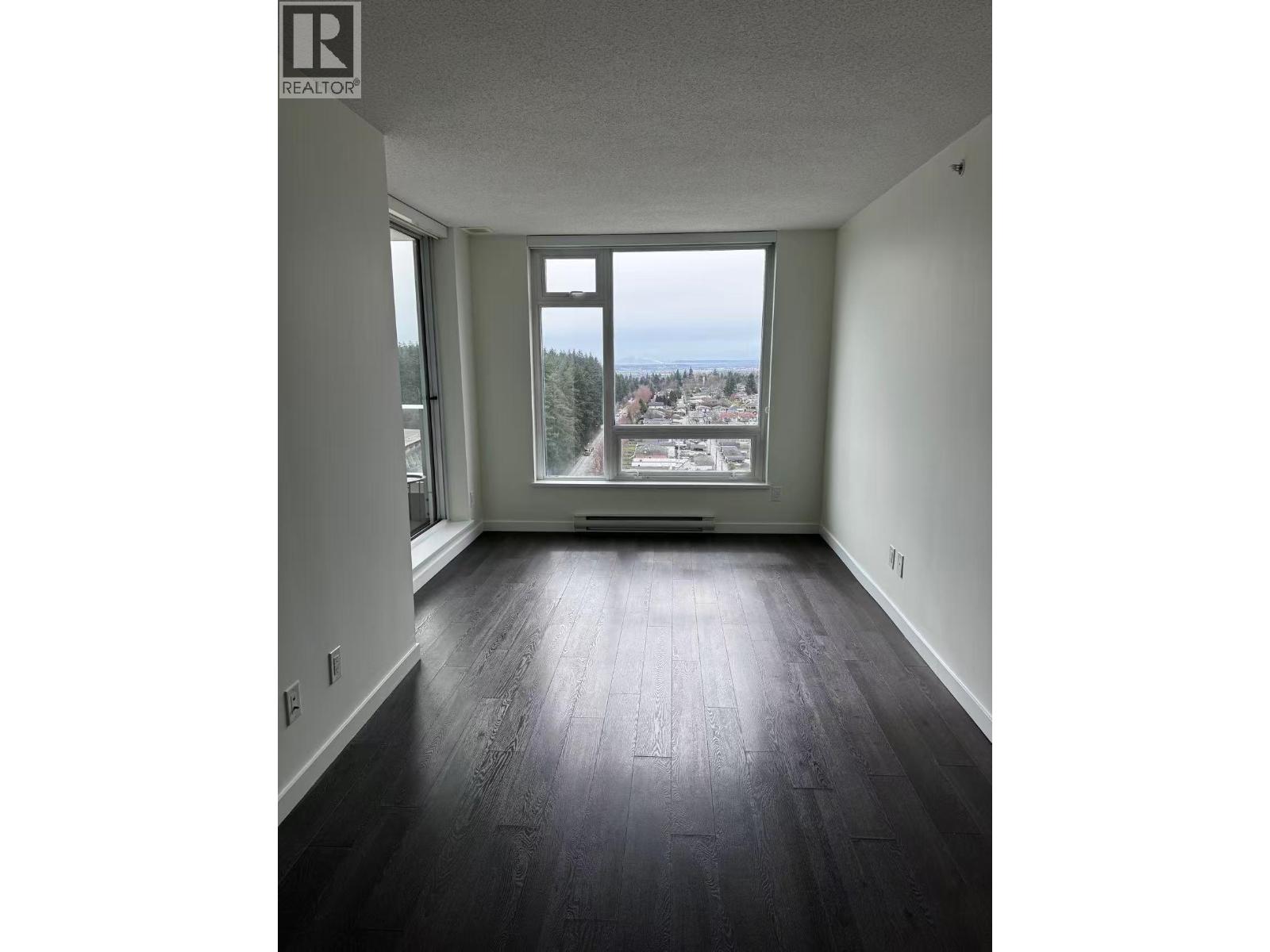 A room with a view of the city and trees.