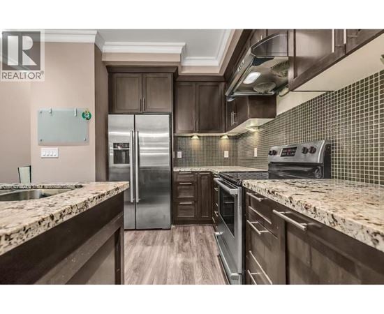 A modern kitchen with granite countertops and stainless steel appliances.