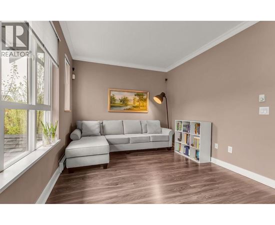 A living room with a grey couch and a painting on the wall.