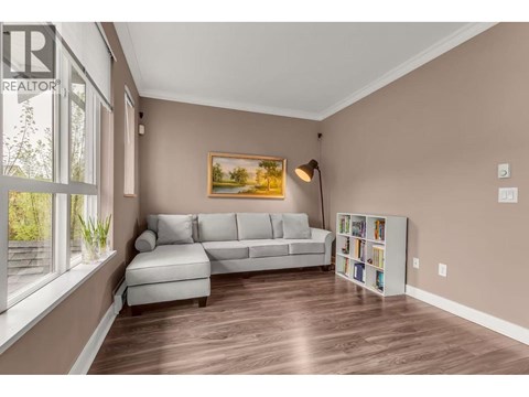 A living room with a grey couch and a painting on the wall.
