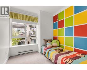 A bedroom with a colorful wall and a window overlooking a balcony.