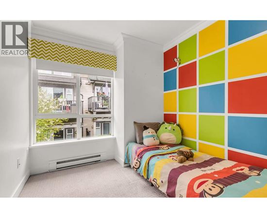 A bedroom with a colorful wall and a window overlooking a balcony.