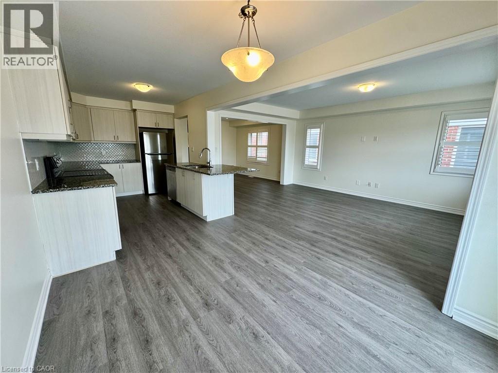 A spacious kitchen and living room with wood flooring and white walls.