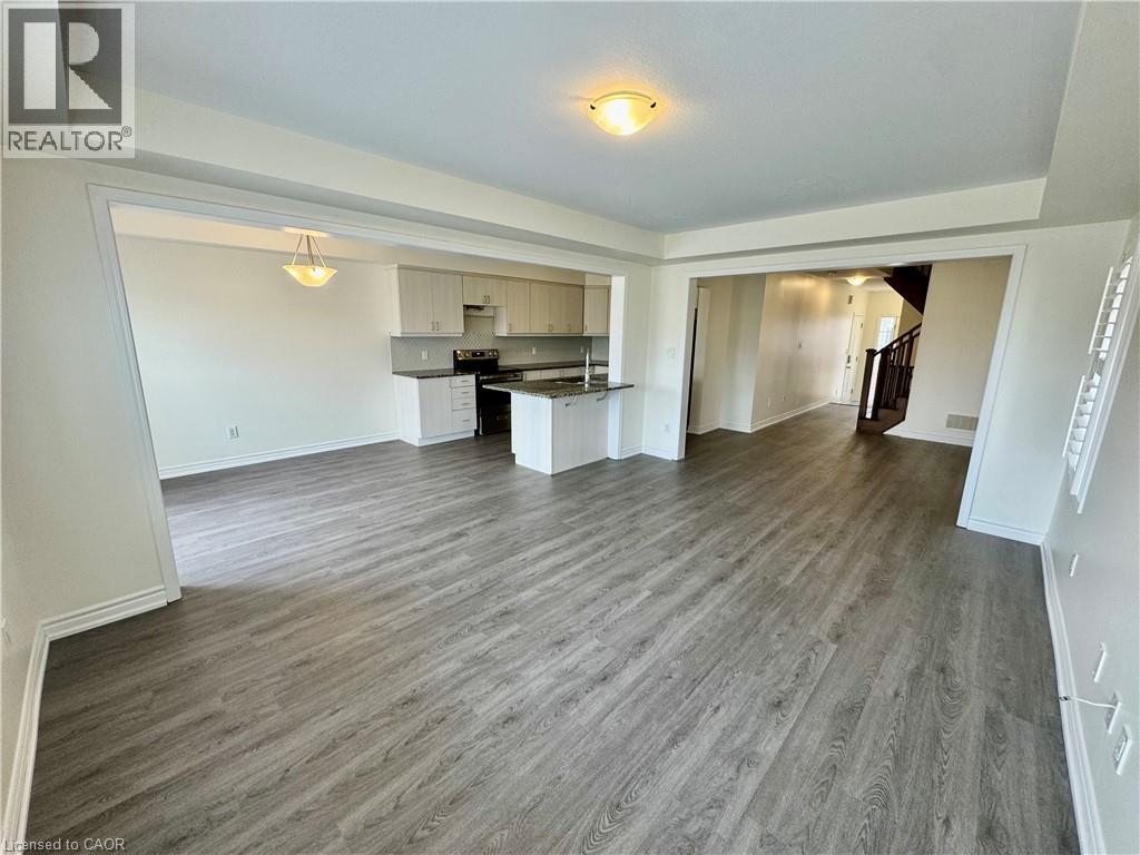 A spacious room with wood flooring and white walls.