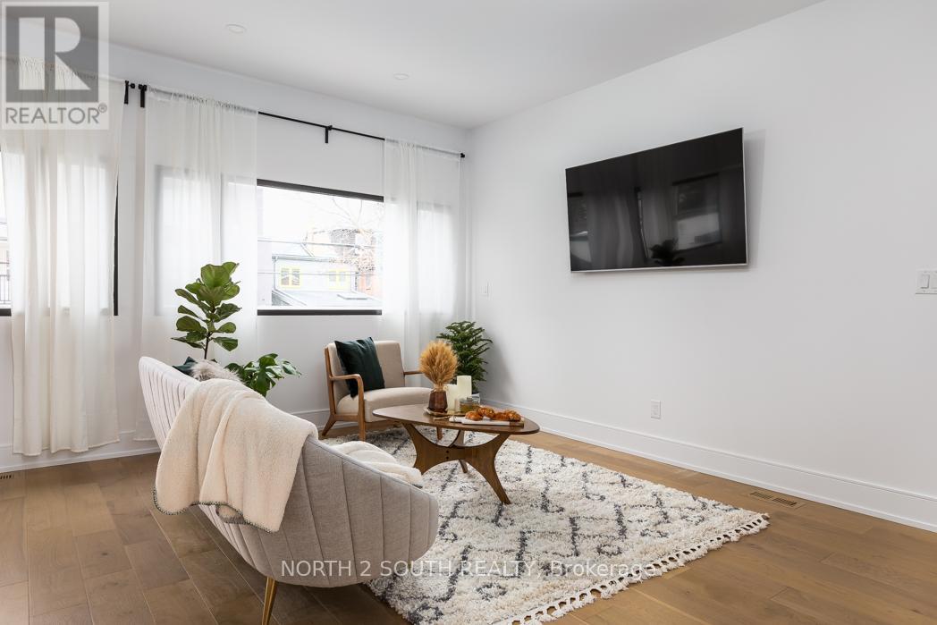 A living room with a grey couch, a wooden coffee table, and a flat screen TV mounted on the wall.