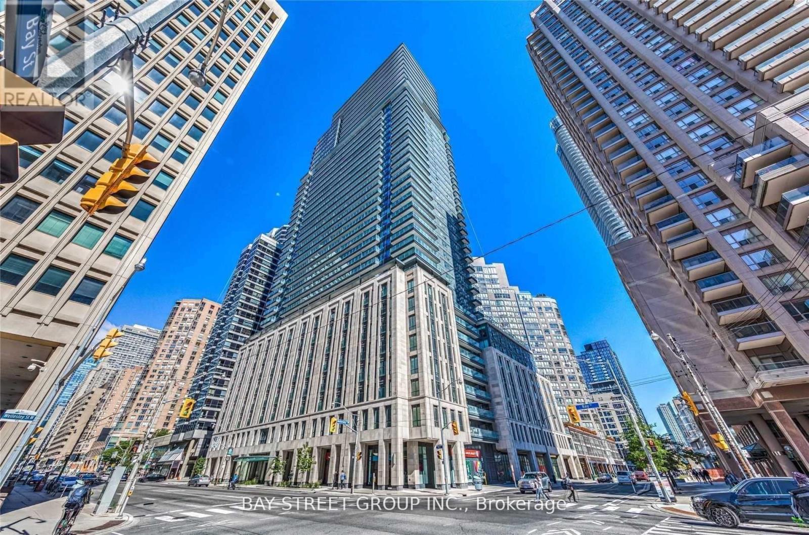 A tall, modern building with a glass facade is the focal point of a bustling city intersection.