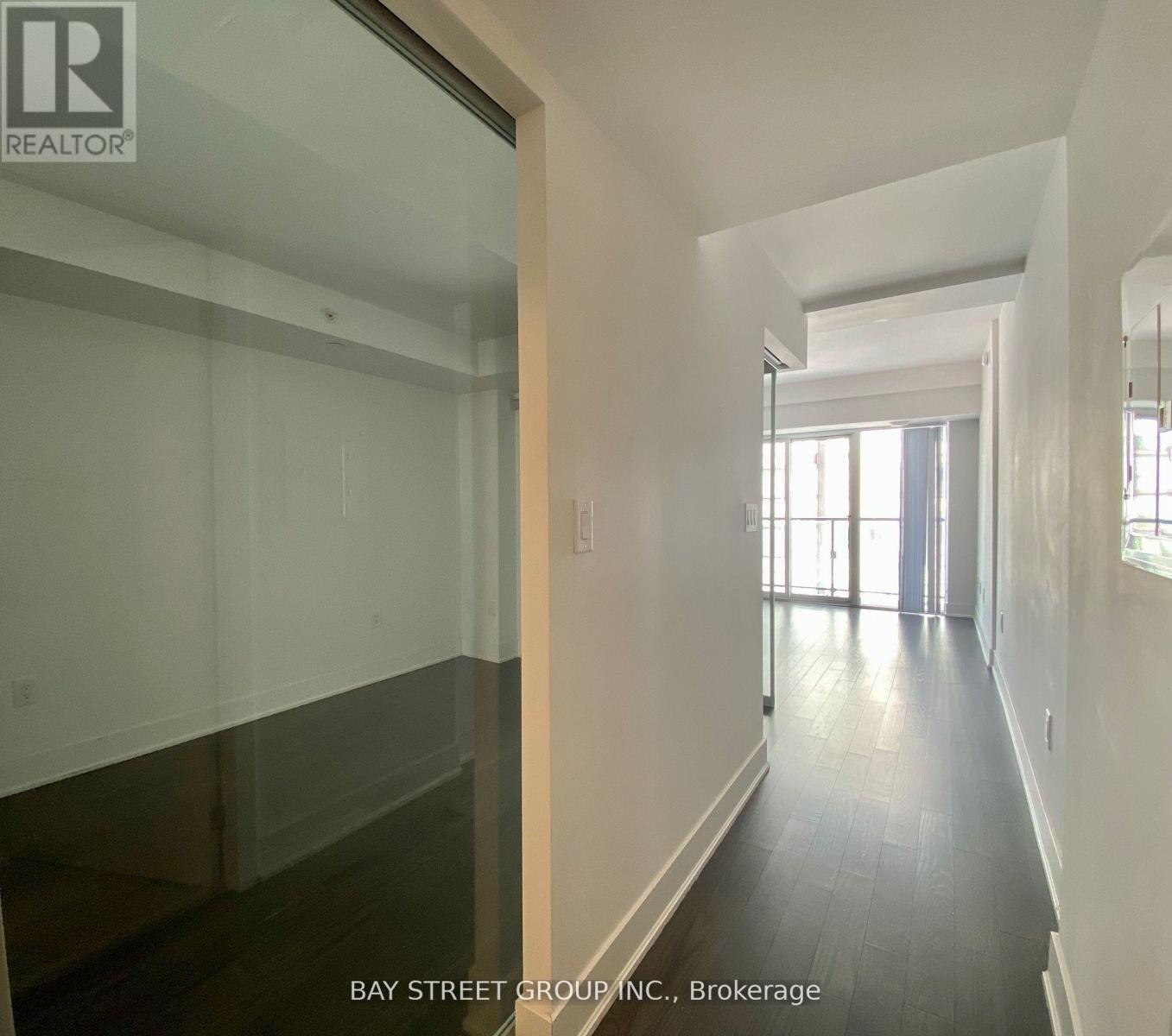 A long hallway with a glass door on the left and a window on the right.