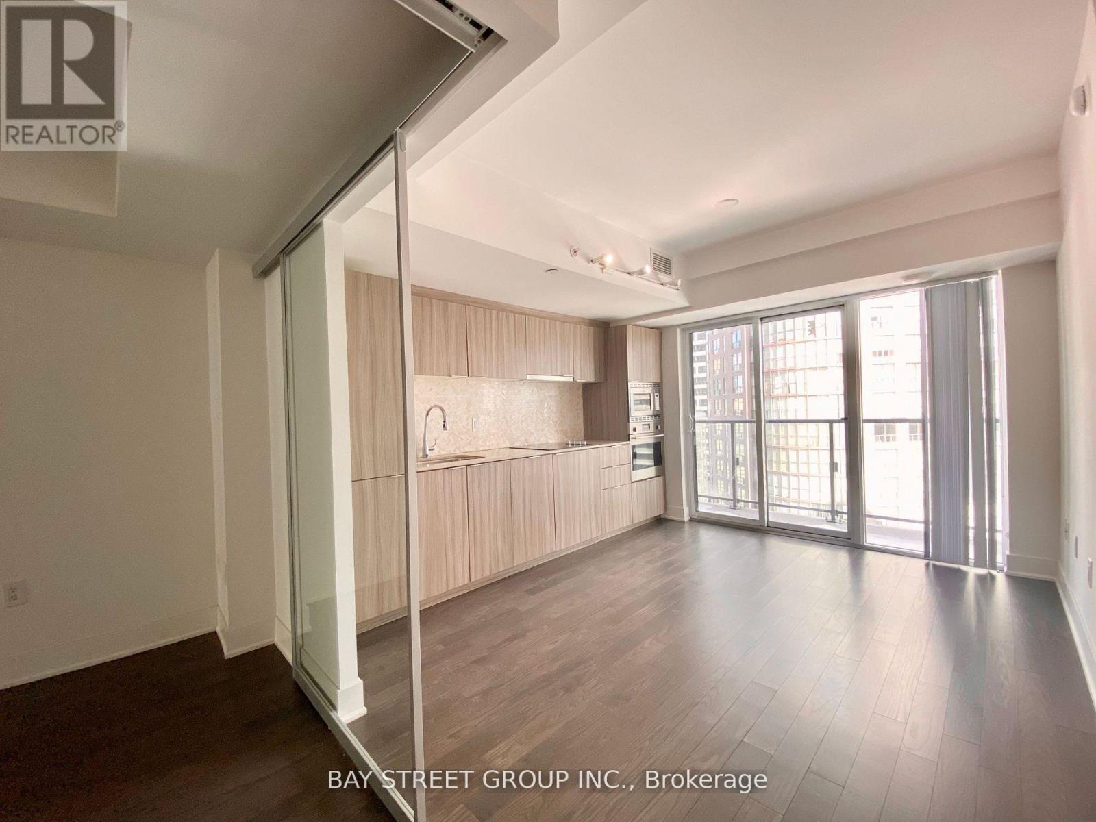 A spacious room with a sliding glass door leading to a balcony.