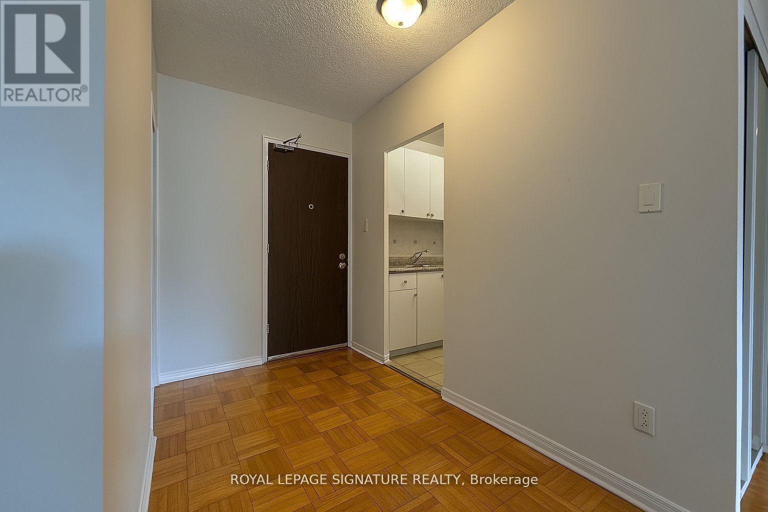 A room with a wooden floor and white walls, with a door and a mirror on the wall.