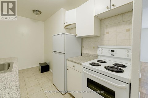 A white kitchen with a stove and a refrigerator.