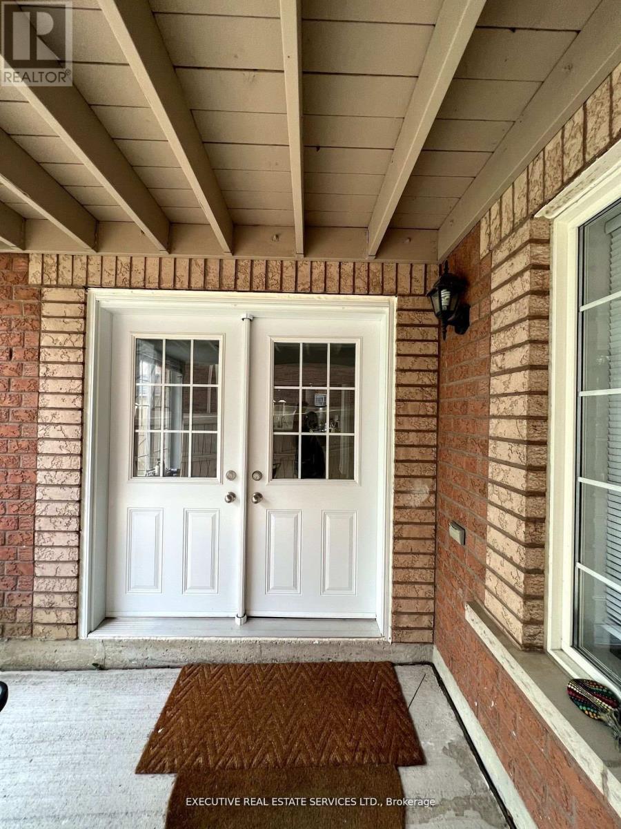 A white double door with a glass panel is on a brick wall.