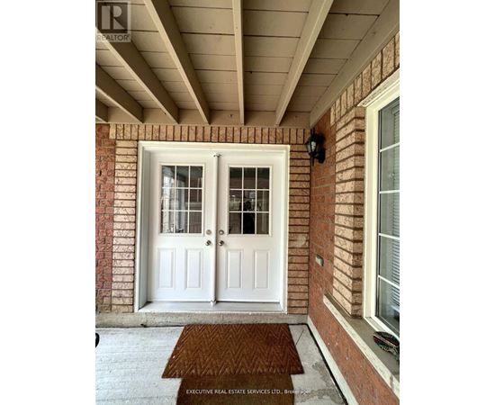 A white double door with a glass panel is on a brick wall.