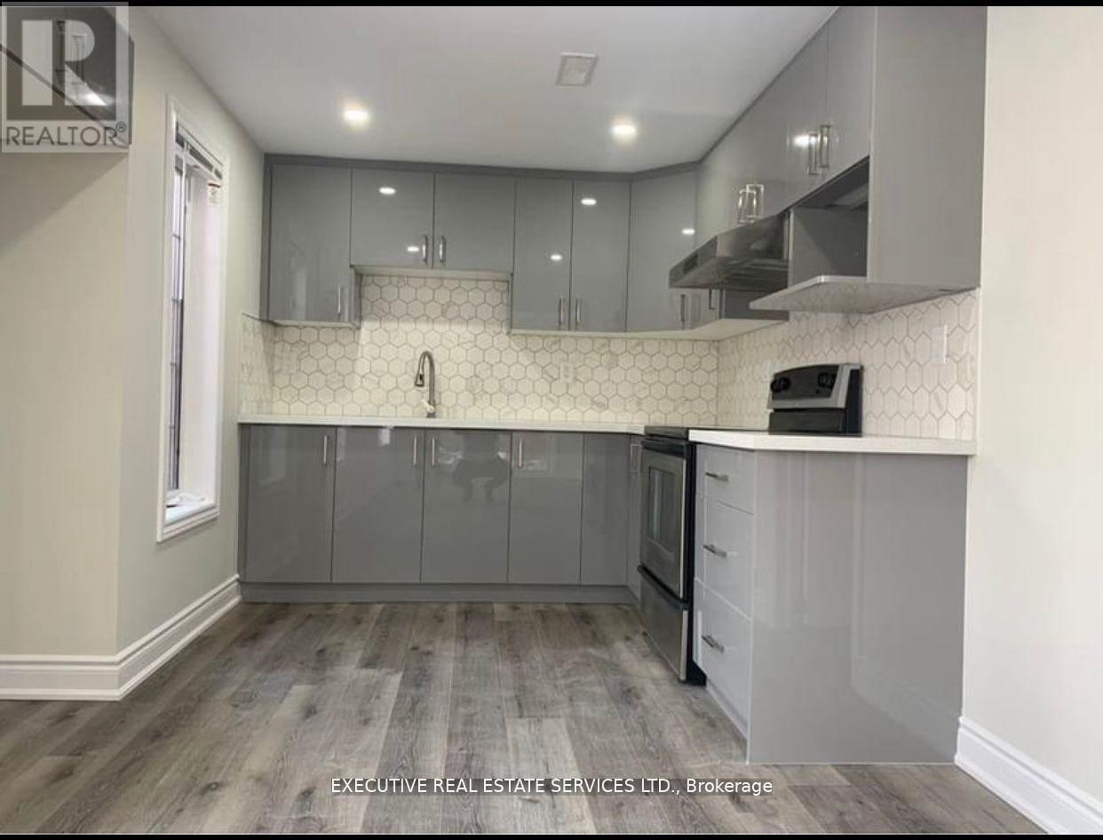 A kitchen with a white tile backsplash and grey cabinets.