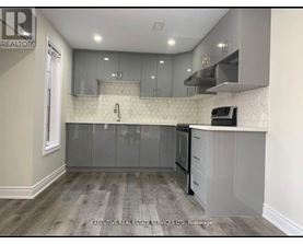 A kitchen with a white tile backsplash and grey cabinets.
