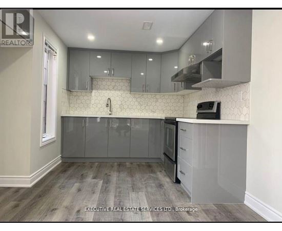 A kitchen with a white tile backsplash and grey cabinets.