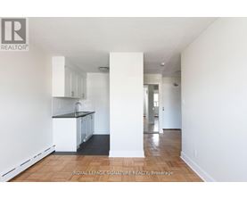 A white interior of a room with a kitchen area and a hallway.