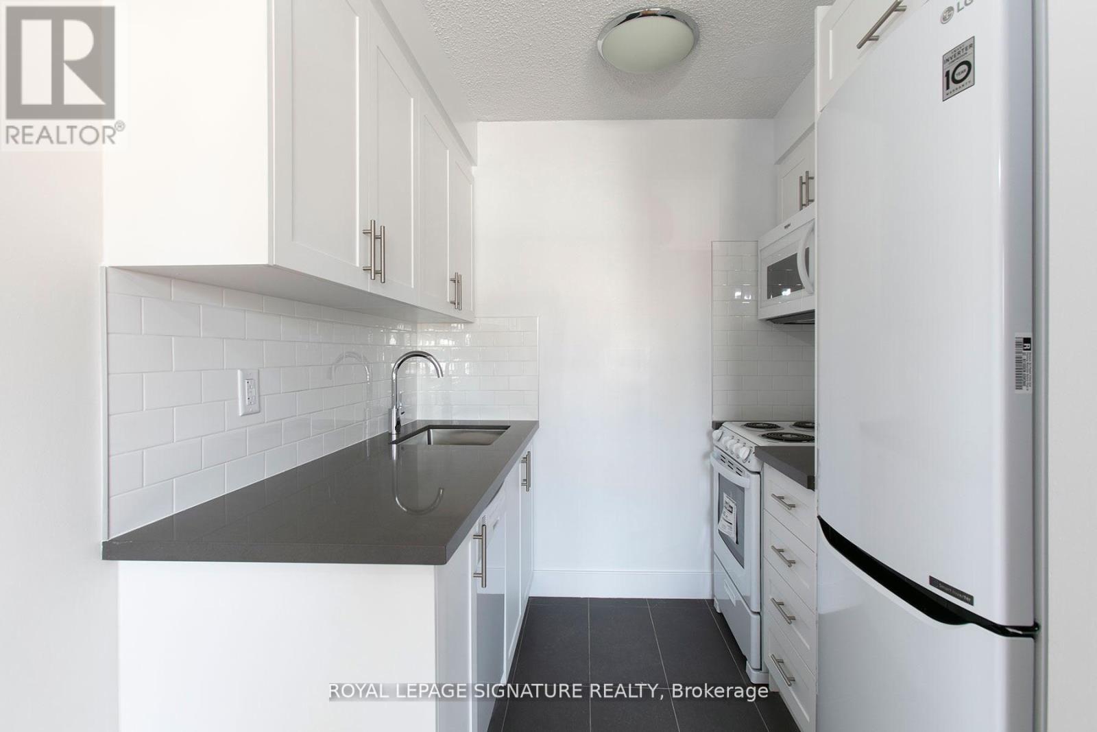 A kitchen with white cabinets and a black counter top.