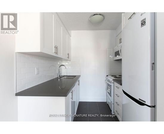 A kitchen with white cabinets and a black counter top.