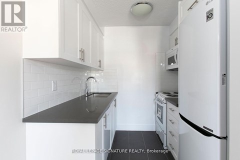 A kitchen with white cabinets and a black counter top.