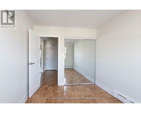 A white hallway with a door on the left and a mirror on the right.