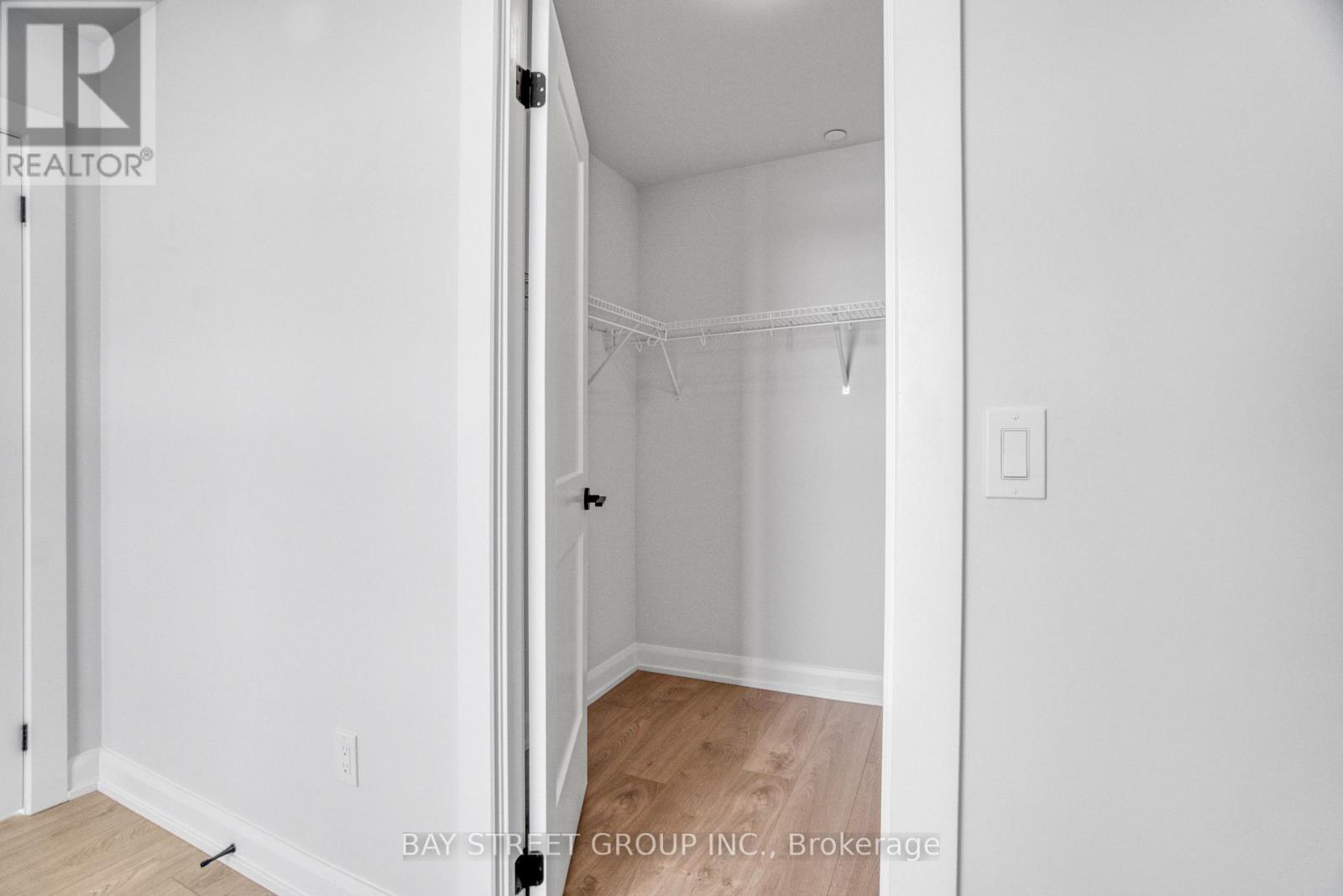 A white bedroom with a doorway open to another room.