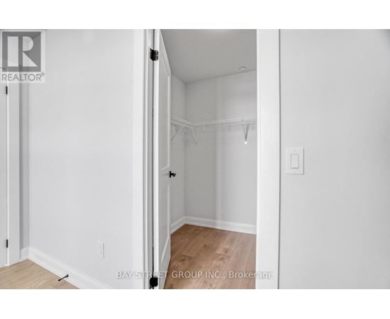 A white bedroom with a doorway open to another room.
