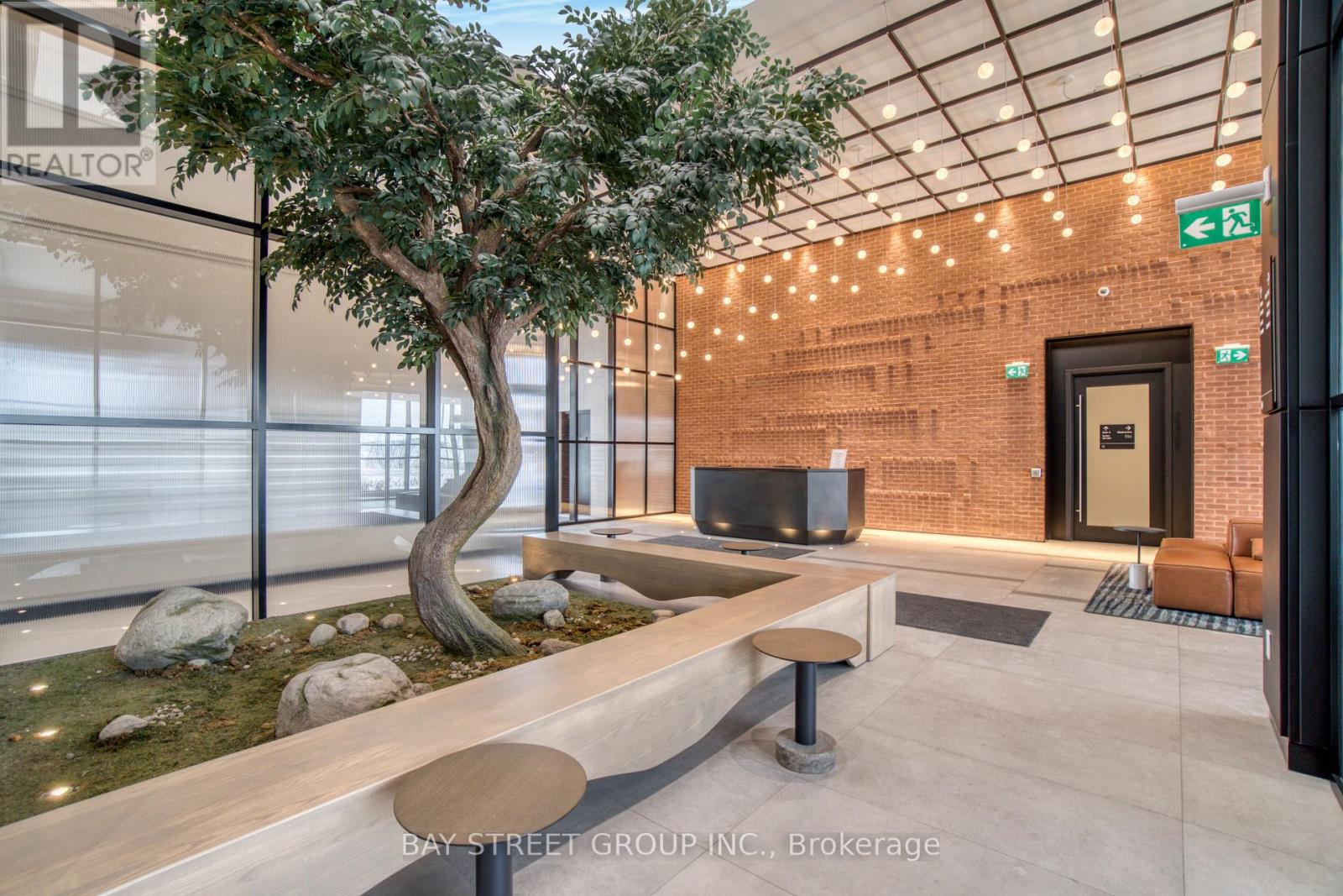 A tree in a planter sits next to a bench in a modern office space.