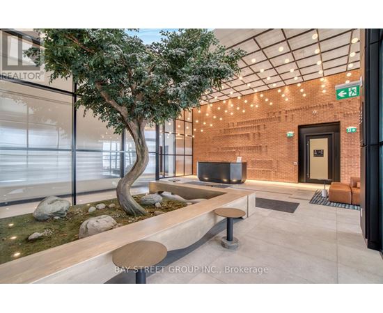 A tree in a planter sits next to a bench in a modern office space.