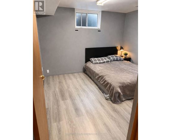 A bedroom with a bed, pillows, and a lamp.