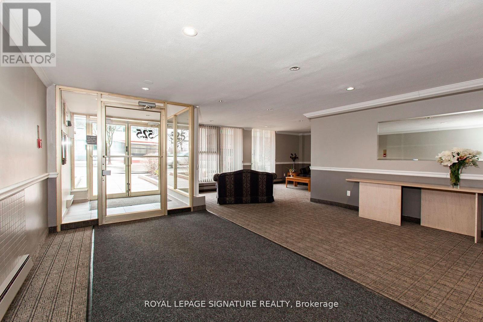 A spacious office room with a glass door entrance and a desk with a vase of flowers on it.
