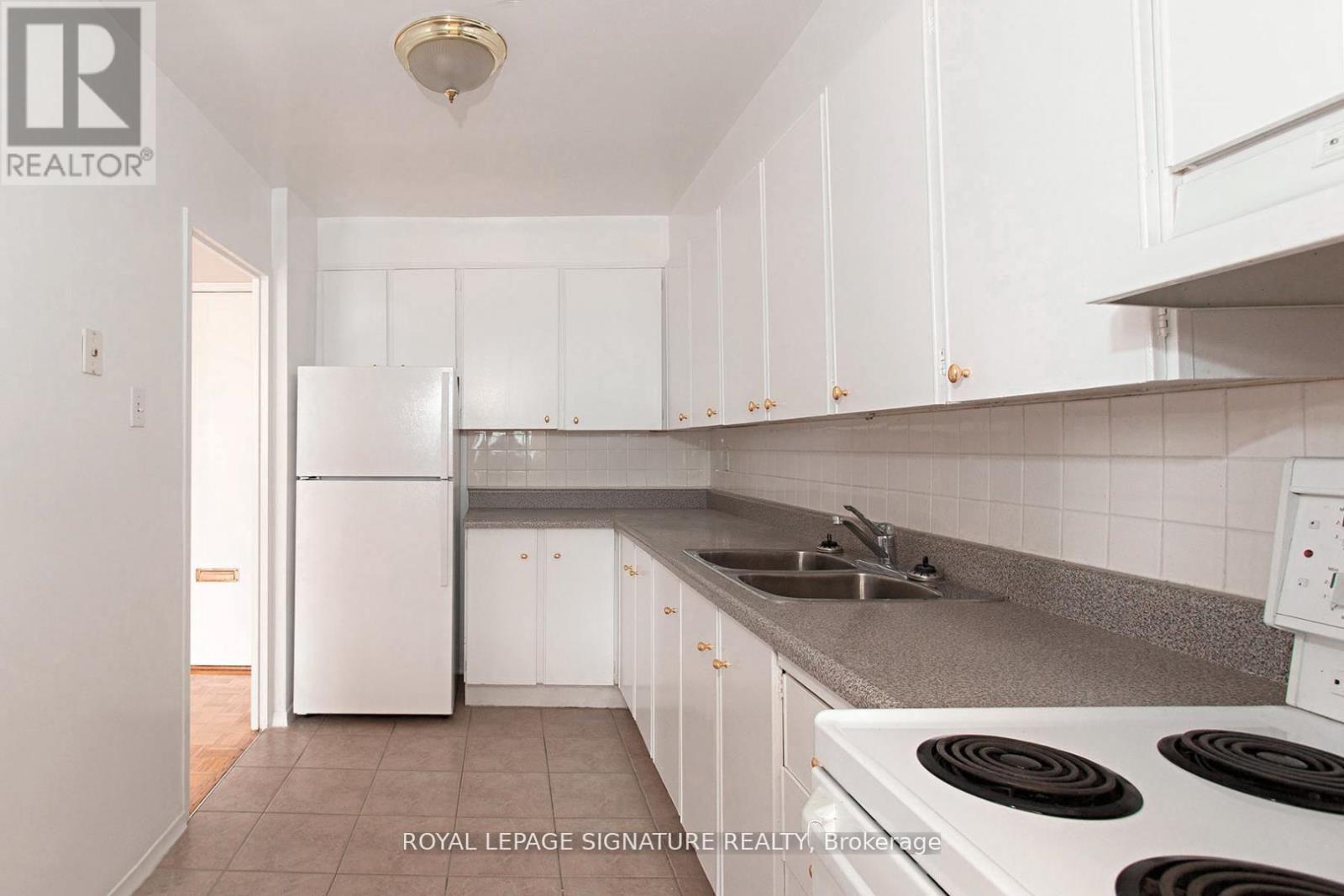 A white kitchen with a refrigerator and stove.