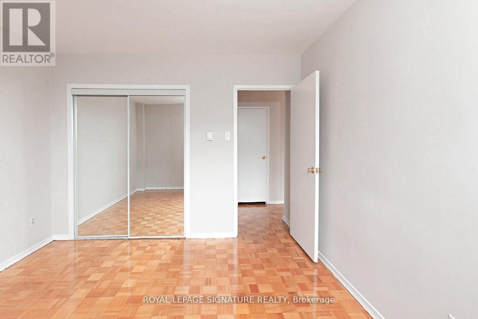 A room with a wooden floor and white walls, with a door on the right and a sliding glass door on the left.