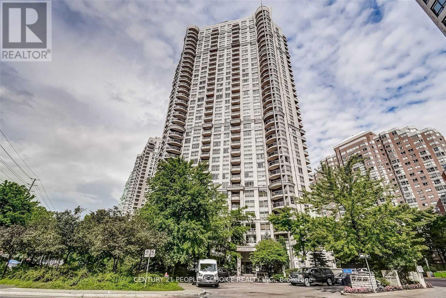 A tall residential building with a parking lot in front.