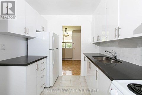 A kitchen with white cabinets and black countertops.